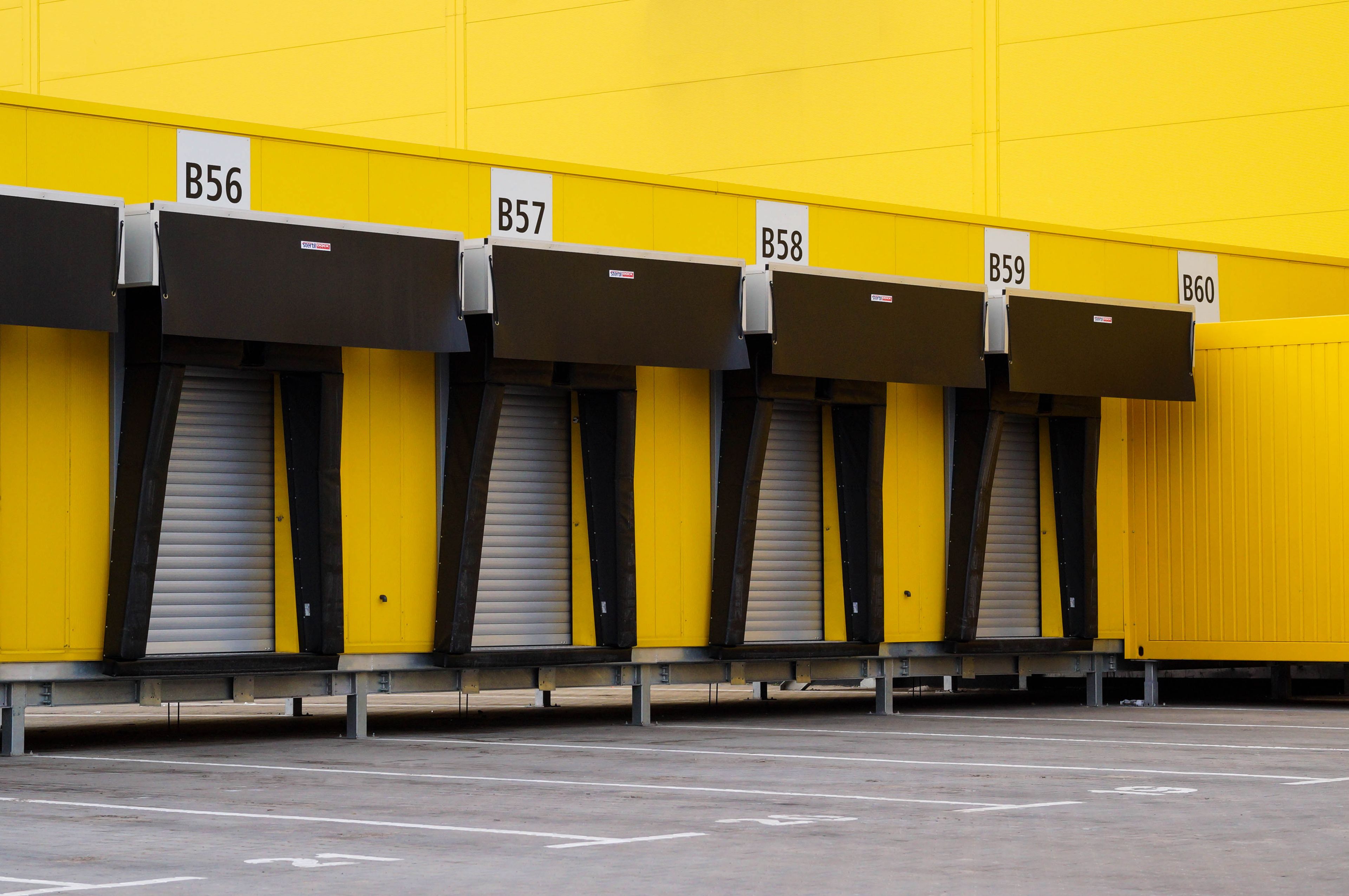 Rangée de portes sectionnelles jaunes numérotées le long d'un quai de chargement