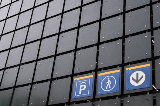 Vista della facciata di un edificio moderno con segnaletica per parcheggi e pedoni che illustra il design urbano.