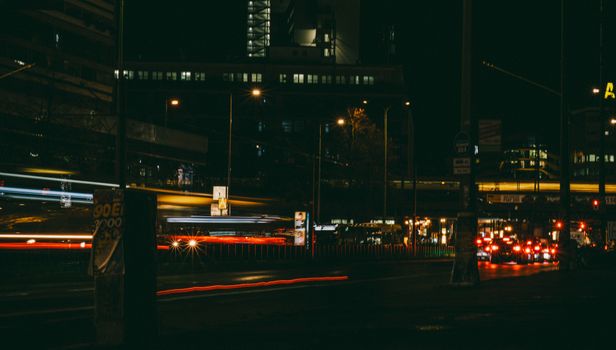 Urban night scene featuring busy city street with light trails and buildings.