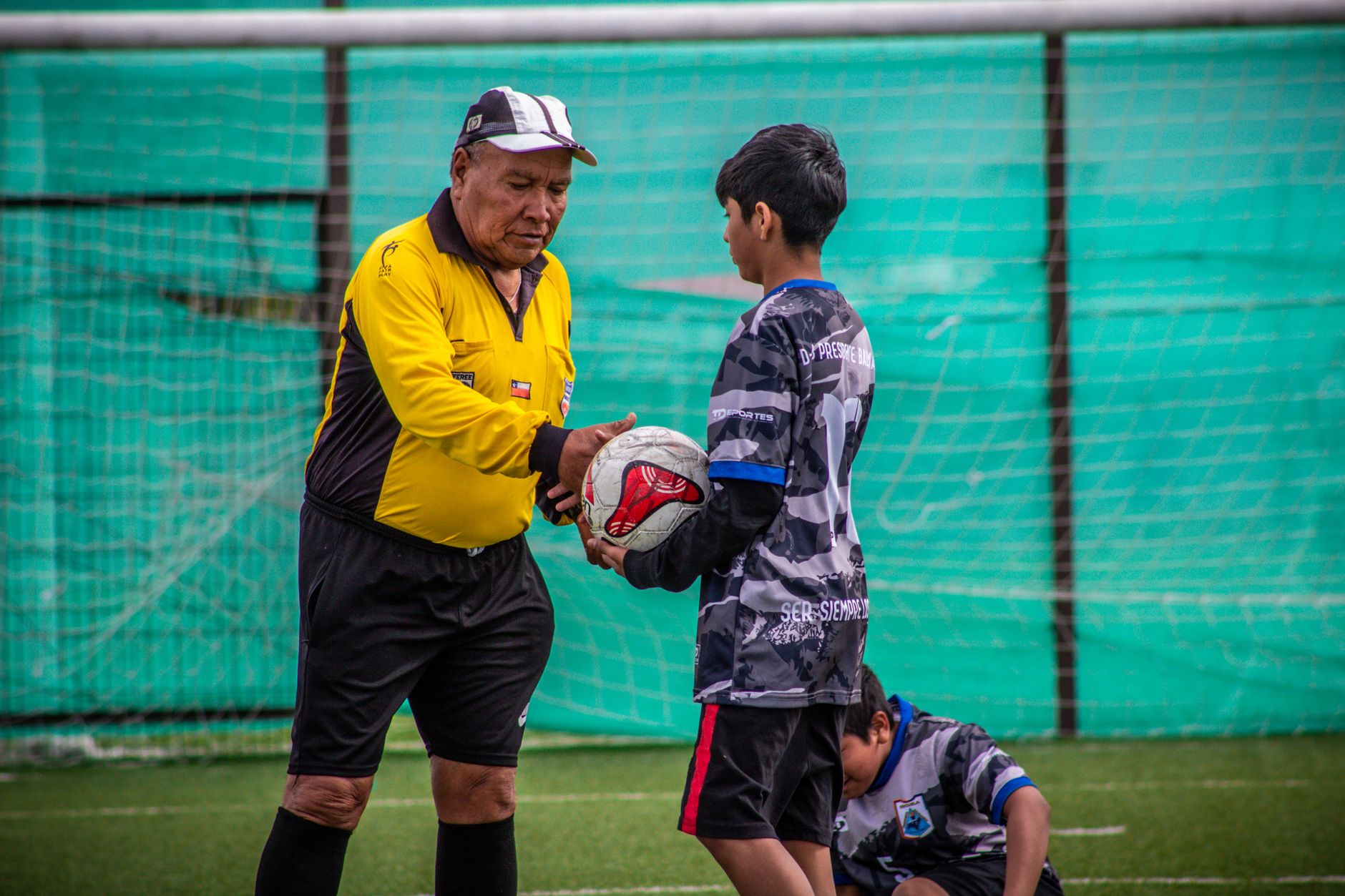 An adult coach and young players during a soccer practice session outdoors in Chile.