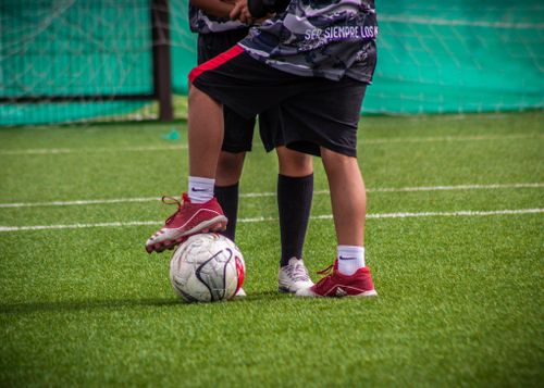 Free Two children playing soccer on a grassy field, focusing on teamwork and fun. Stock Photo