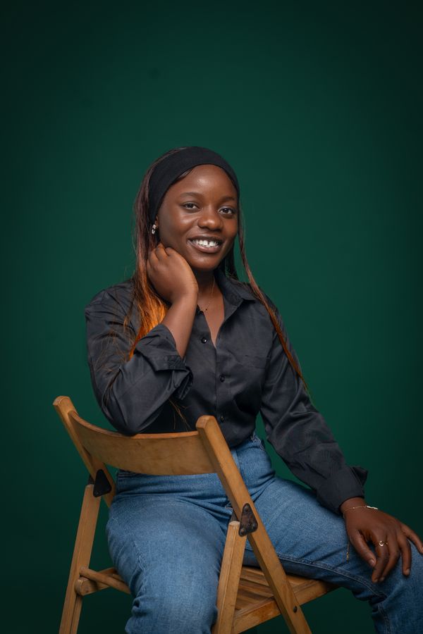 Smiling member seated against a deep green backdrop — photo by Daniel Sunga on Pexels
