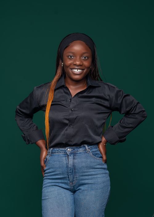 Free Smiling woman in casual outfit stands confidently against a green background. Stock Photo