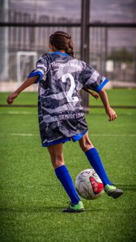 Young girl playing soccer on a sunny day wearing blue uniform. Action shot.