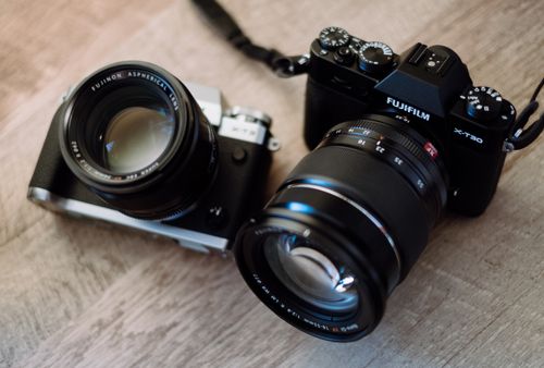 Free Detailed view of two Fujifilm cameras on a wooden surface, showcasing lenses and dials. Stock Photo
