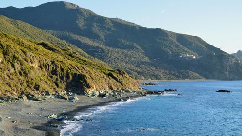 Free A breathtaking coastal view in Ogliastro, Corsica, featuring lush green mountains and blue sea. Stock Photo