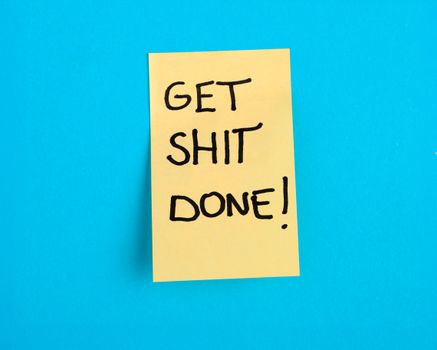 Yellow sticky note with motivational message on a bright blue background.