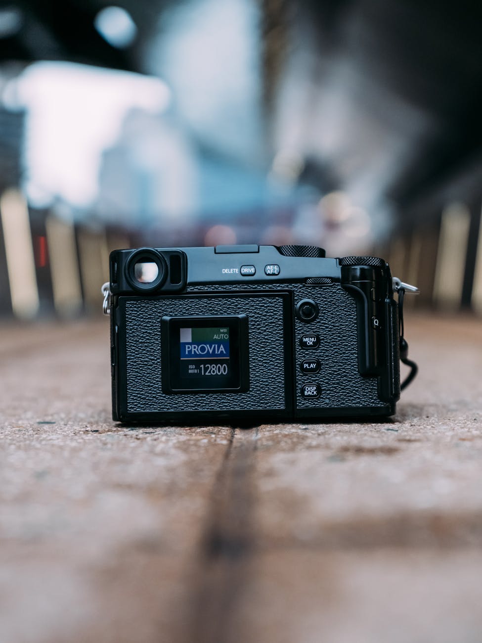 Close-up shot of a vintage film camera placed on an urban street, displaying manual settings.