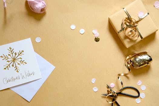 A festive flat lay of Christmas gift wrapping essentials with a card, ribbon, and confetti.