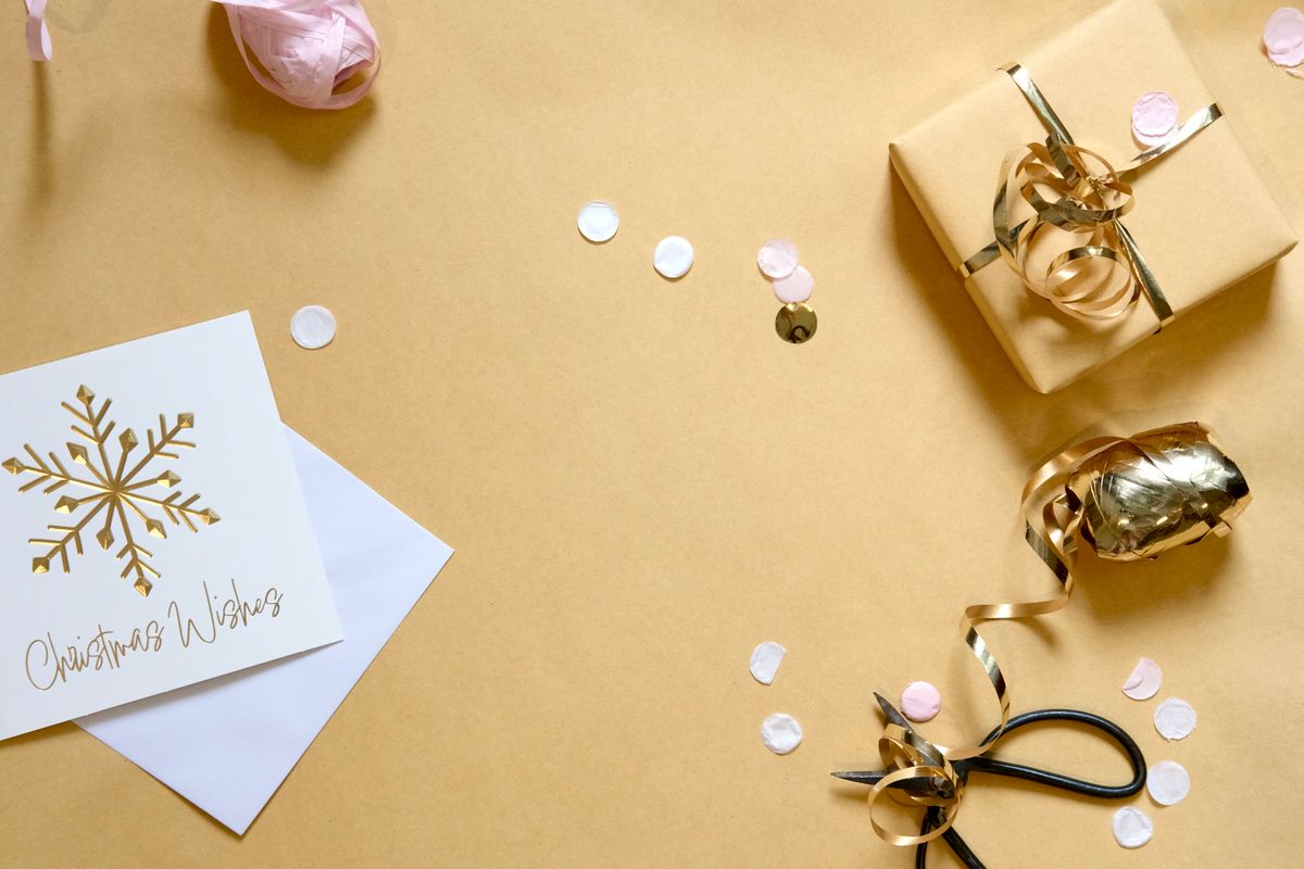 Festive Christmas gift wrapping essentials including ribbon, a card, and confetti arranged flat