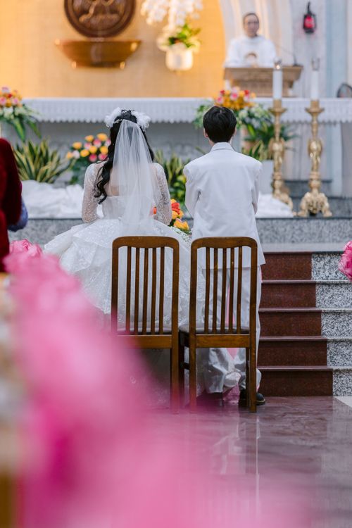Free Bride and groom kneel during a wedding ceremony in a beautifully decorated church. Stock Photo