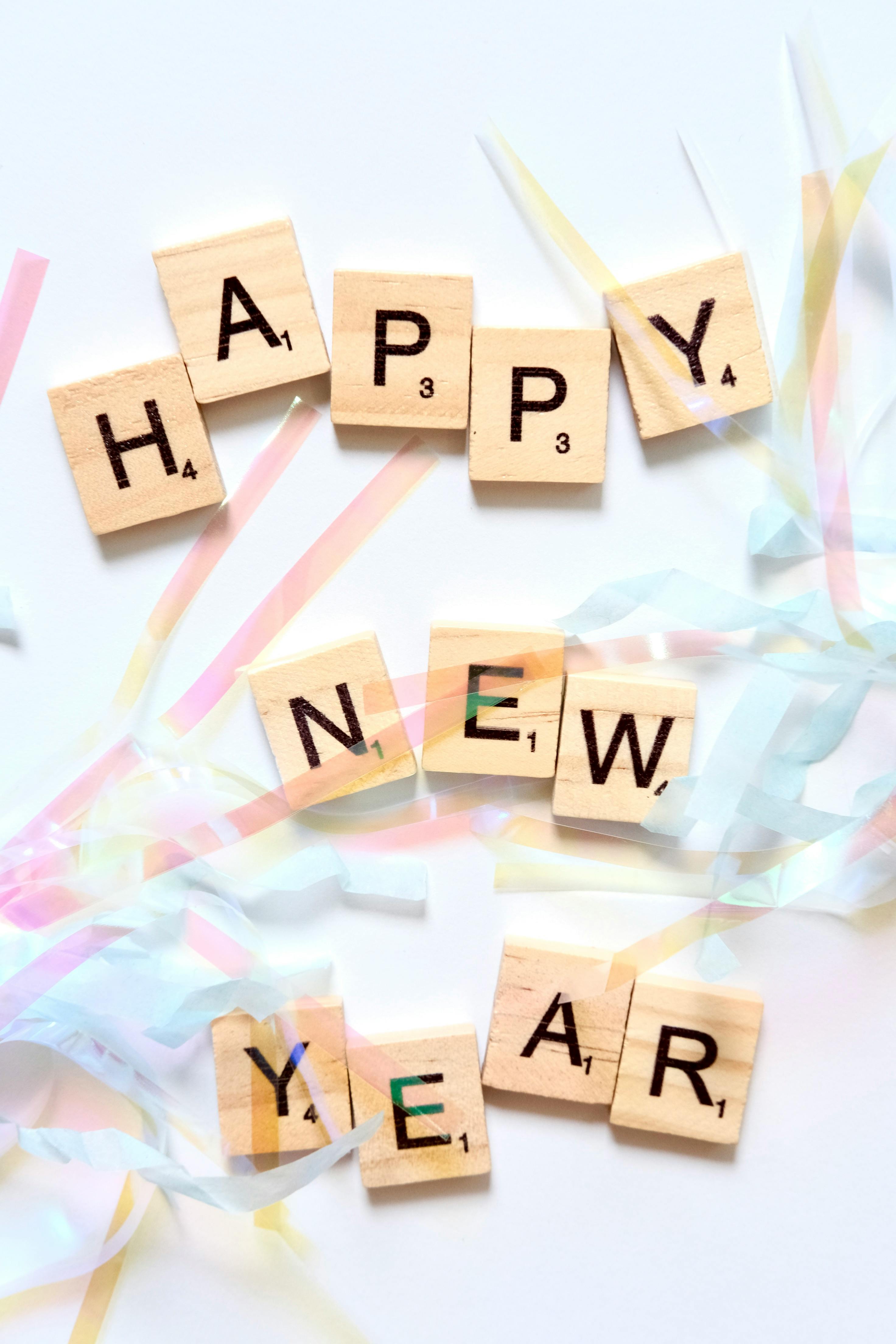 Scrabble letters forming 'Happy New Year' with colorful ribbons.