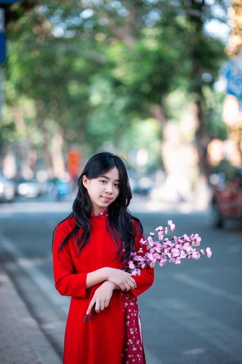 Young Woman in Red Dress Holding Blossoms on Street · Free Stock Photo