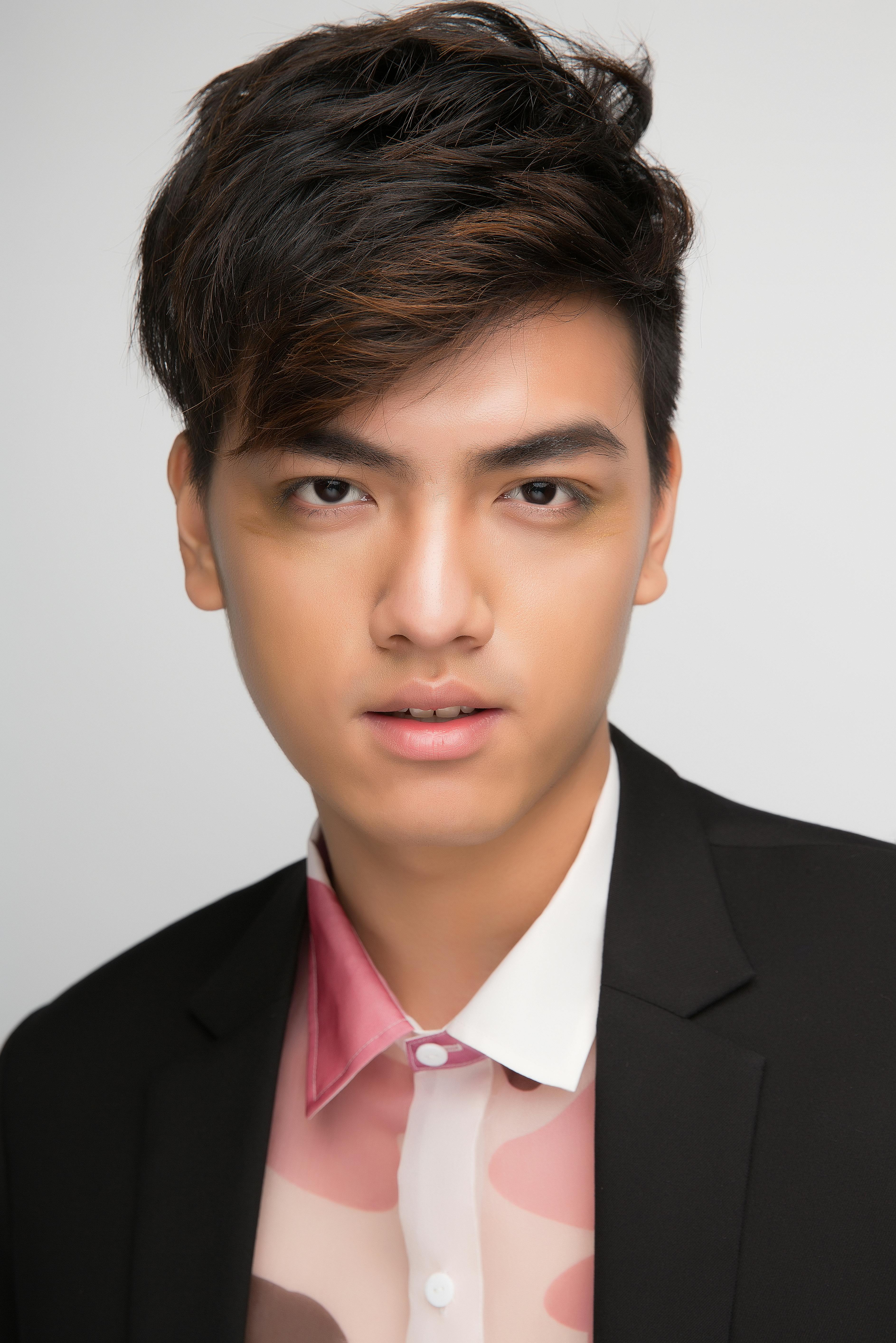 Close-up portrait of a young man wearing a stylish outfit, looking directly at the camera.