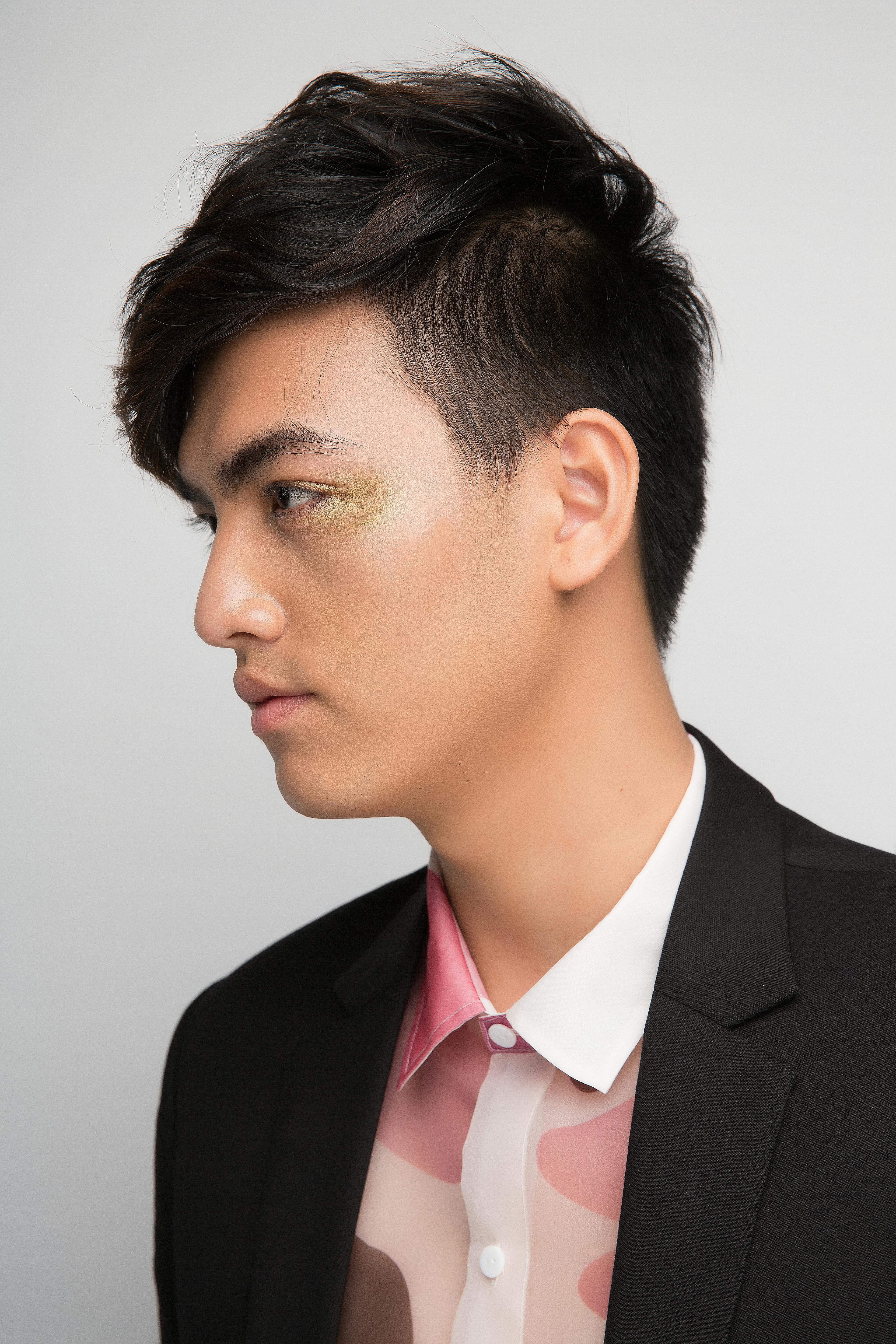 Profile portrait of a stylish young man wearing a suit with artistic lighting.