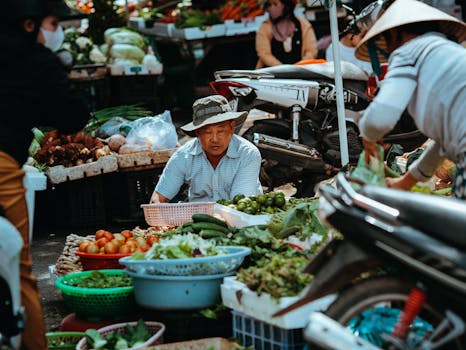 A bustling outdoor market scene in Kon Tum, Vietnam showcasing fresh vegetables and local vendors.