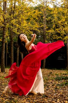 A woman gracefully dances amidst a vibrant autumn forest, capturing the essence of movement and nature.
