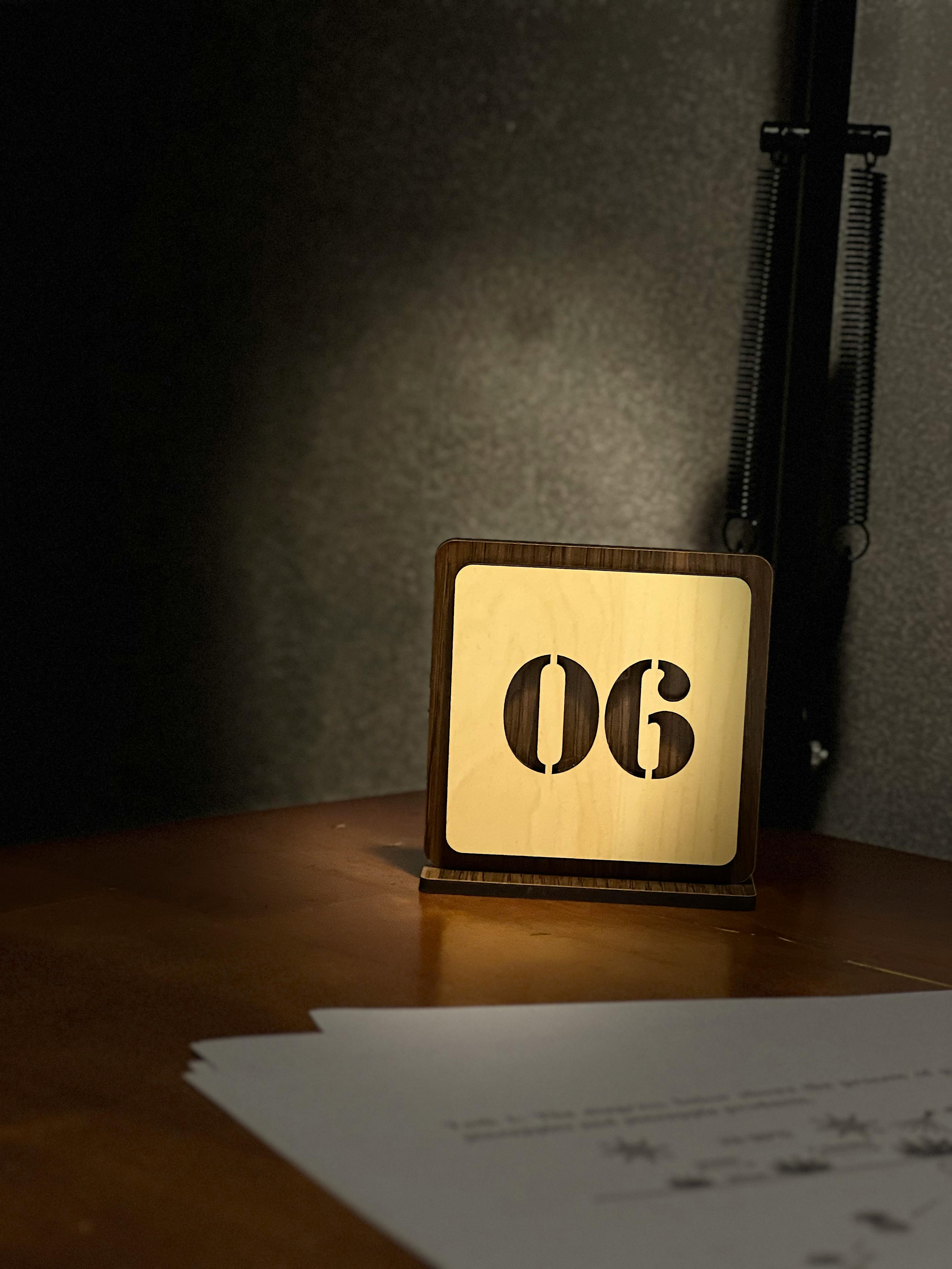 Kostnadsfria En minimalistisk trälampa lyser mjukt upp ett bord i ett mysigt, svagt upplyst utrymme. Stock foto