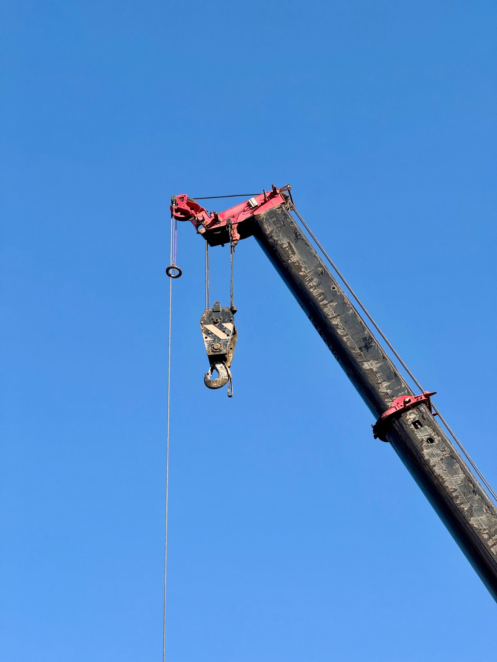 Crane boom and hook against a blue sky