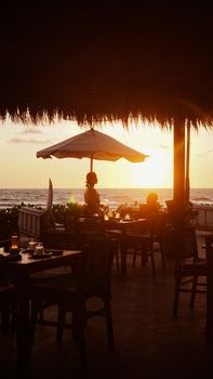 Serene beachside restaurant setting with silhouette of people at sunset.