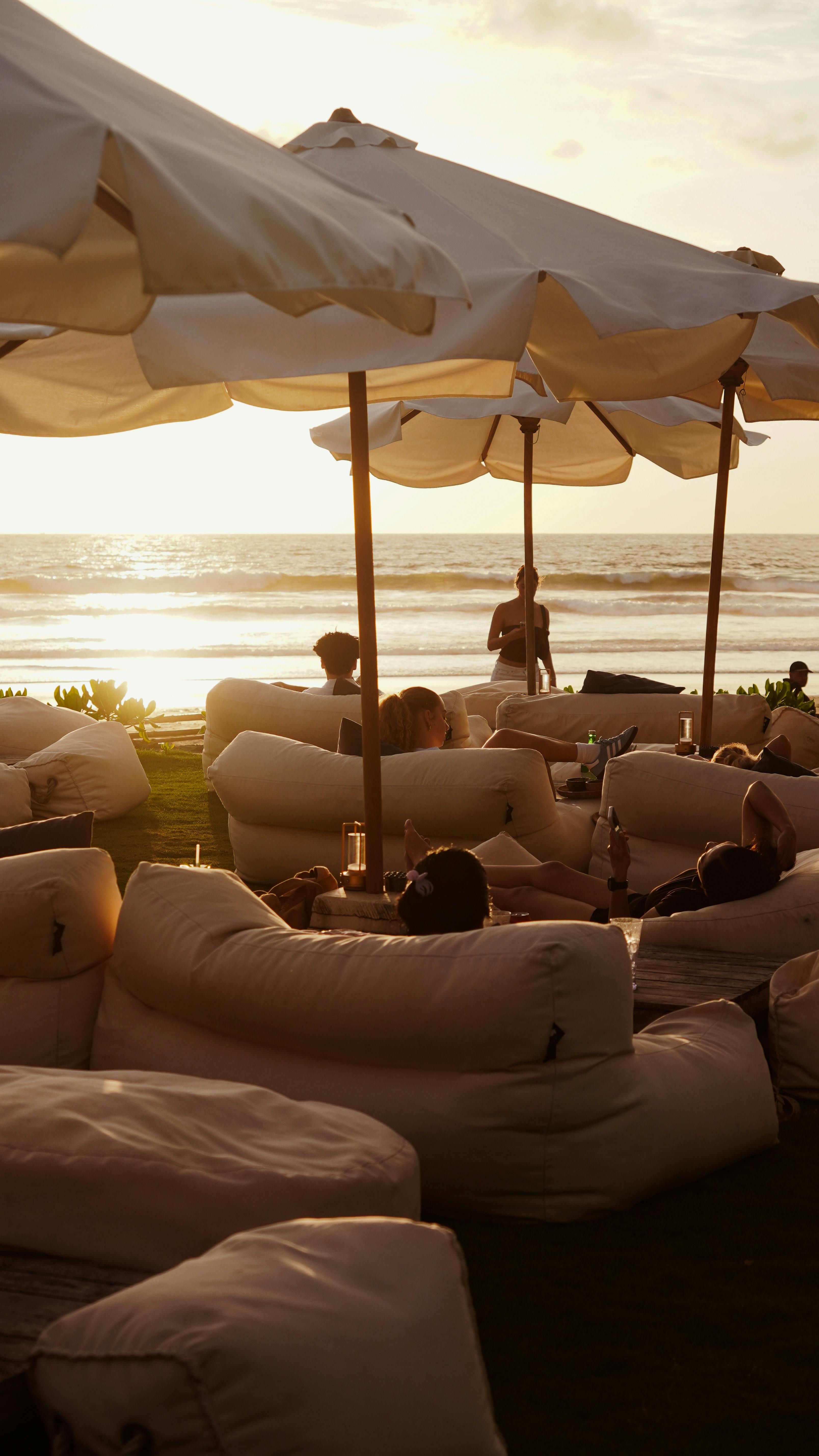 Sunset view from a Seminyak beach club with daybeds and lanterns facing the Indian Ocean — the polished beachfront vibe that defines Seminyak