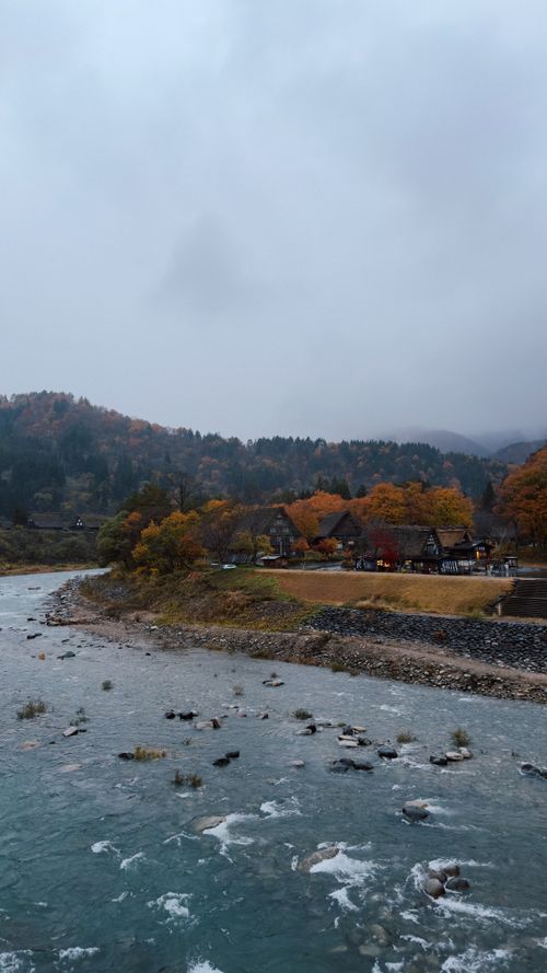 Free Picturesque view of Shirakawa-go village with autumn colors and a serene river. Stock Photo