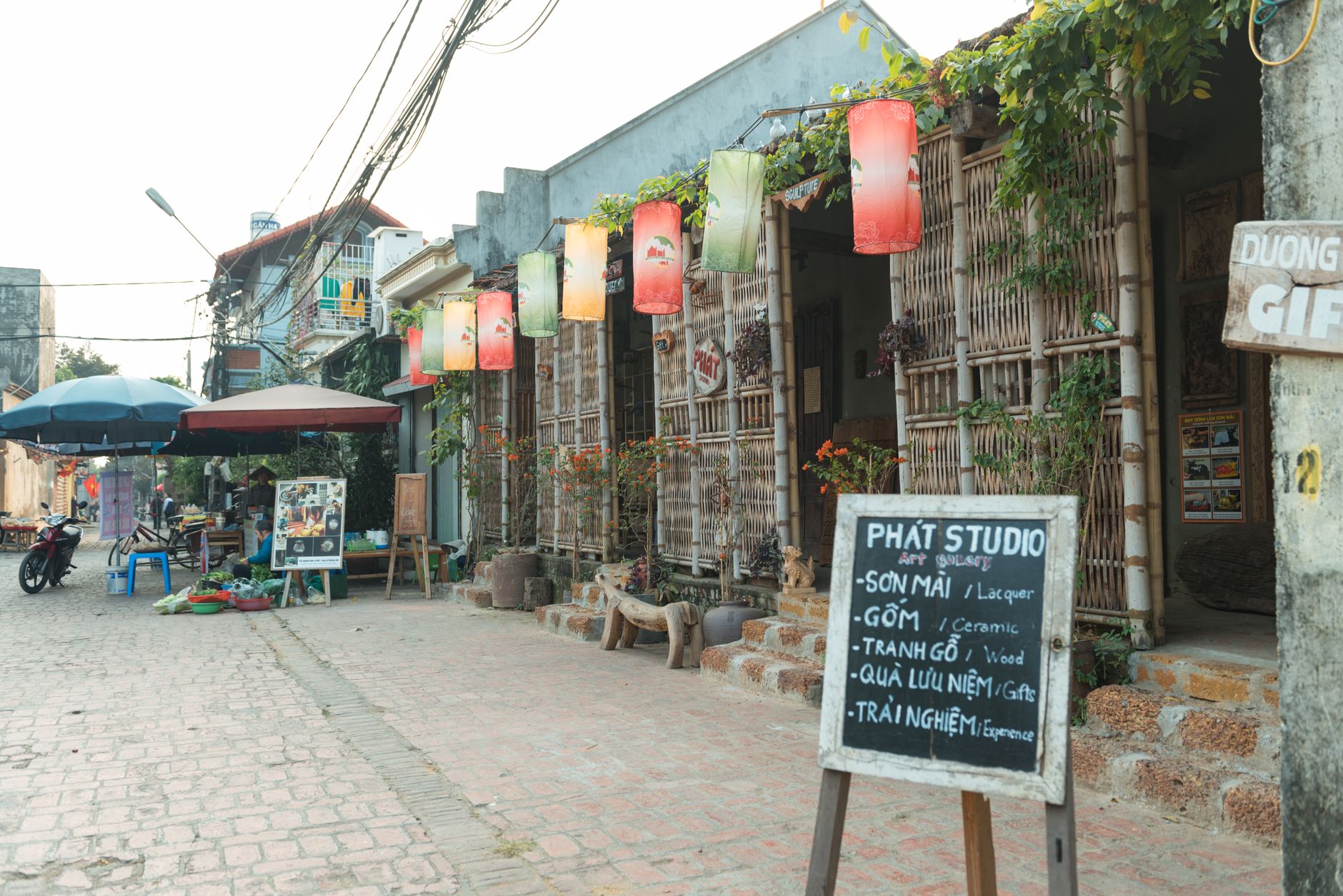 A vibrant Hanoi street with an art studio, colorful lanterns, and local shops.