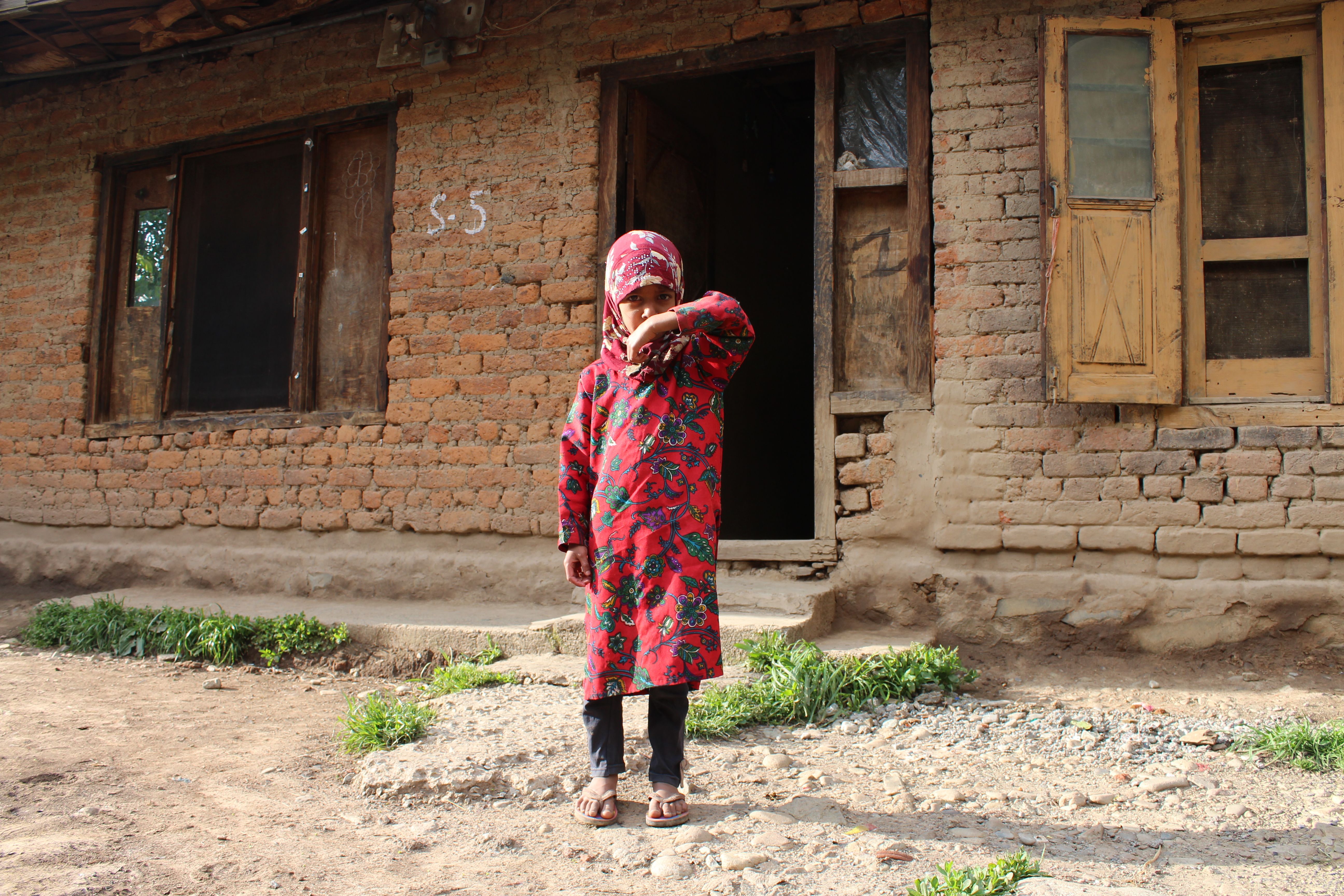 Child in Traditional Dress in Rustic Setting · Free Stock Photo