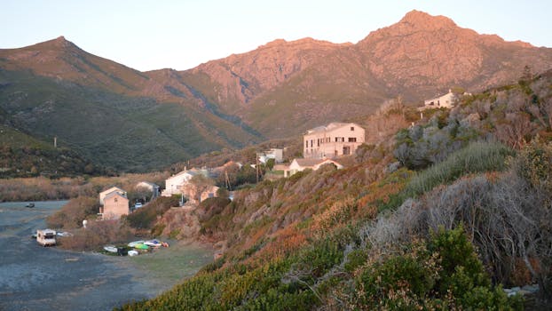 Charming view of Ogliastro village with mountainous backdrop in Corse, France at dusk.