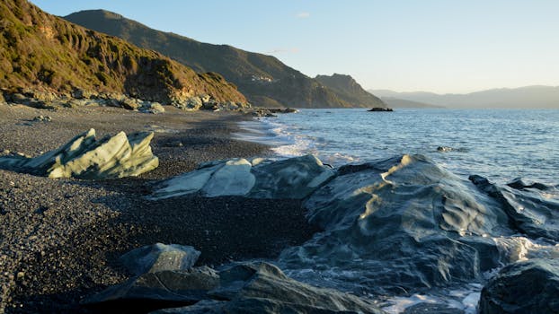 Beautiful coastal landscape in Ogliastro, Corse, France. Rocky shoreline with waves under a golden sunset.