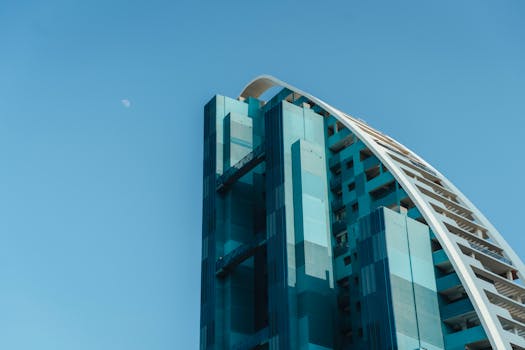 View of a modern architectural building with blue facade under clear blue sky and visible moon.