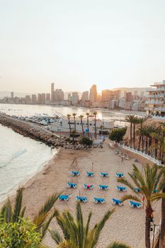 A serene beachfront view overlooking a city skyline with a beautiful sunset backdrop.