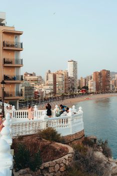 Captivating view of Benidorm's coastal skyline at dusk with tourists enjoying the sunset.