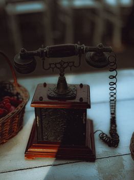 A beautifully crafted vintage rotary telephone on a wooden table with a wicker basket, shot in Ernakulam, India.