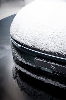 Close-up of a snow-covered electric luxury car in an Amsterdam dealership setting, showcasing modern elegance.