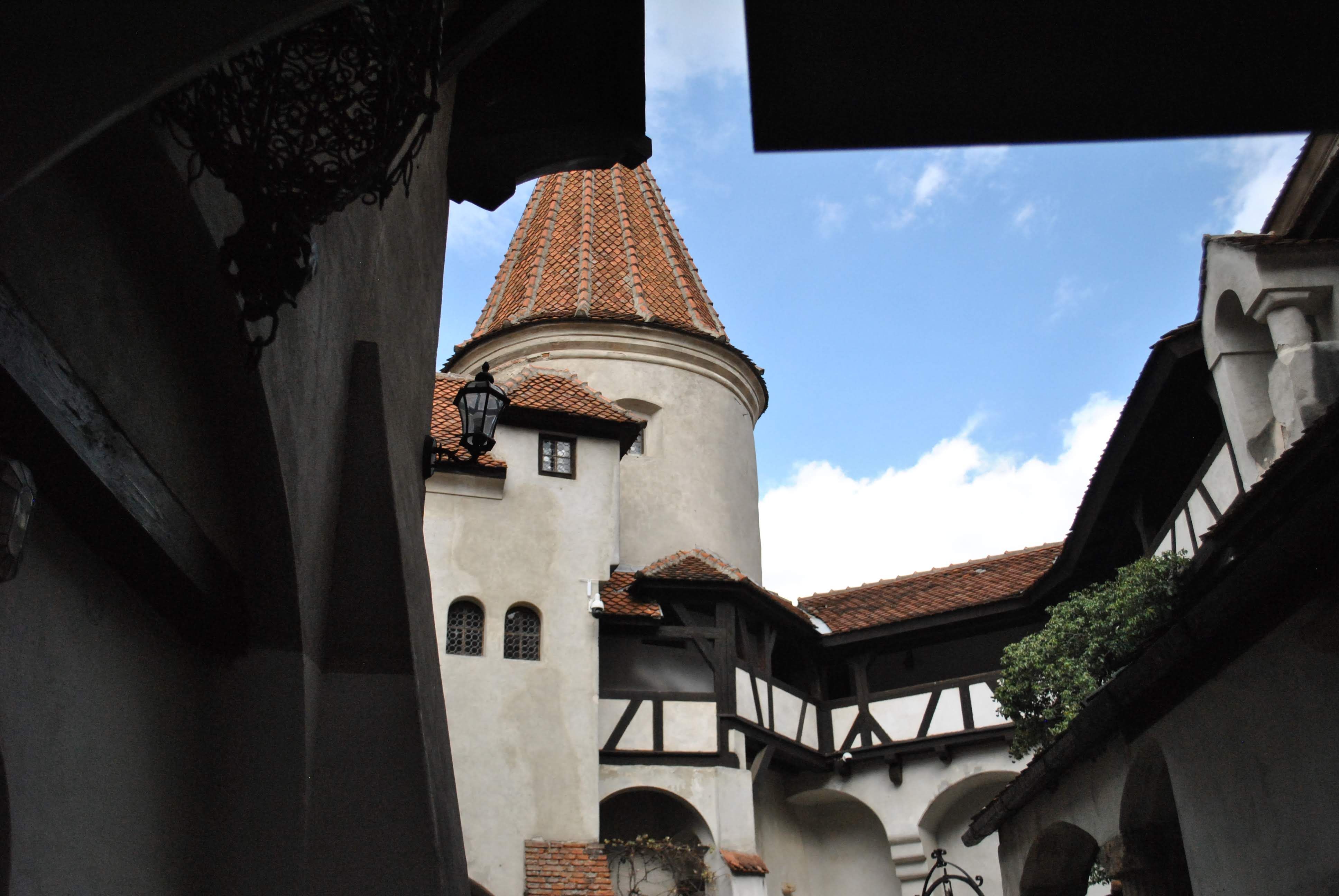 Charming view of a medieval castle courtyard with a picturesque tower and blue sky.