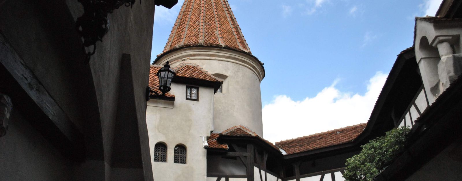 Charming view of a medieval castle courtyard with a picturesque tower and blue sky.