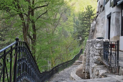 Free A picturesque winding path by mountain buildings, surrounded by lush greenery in spring. Stock Photo