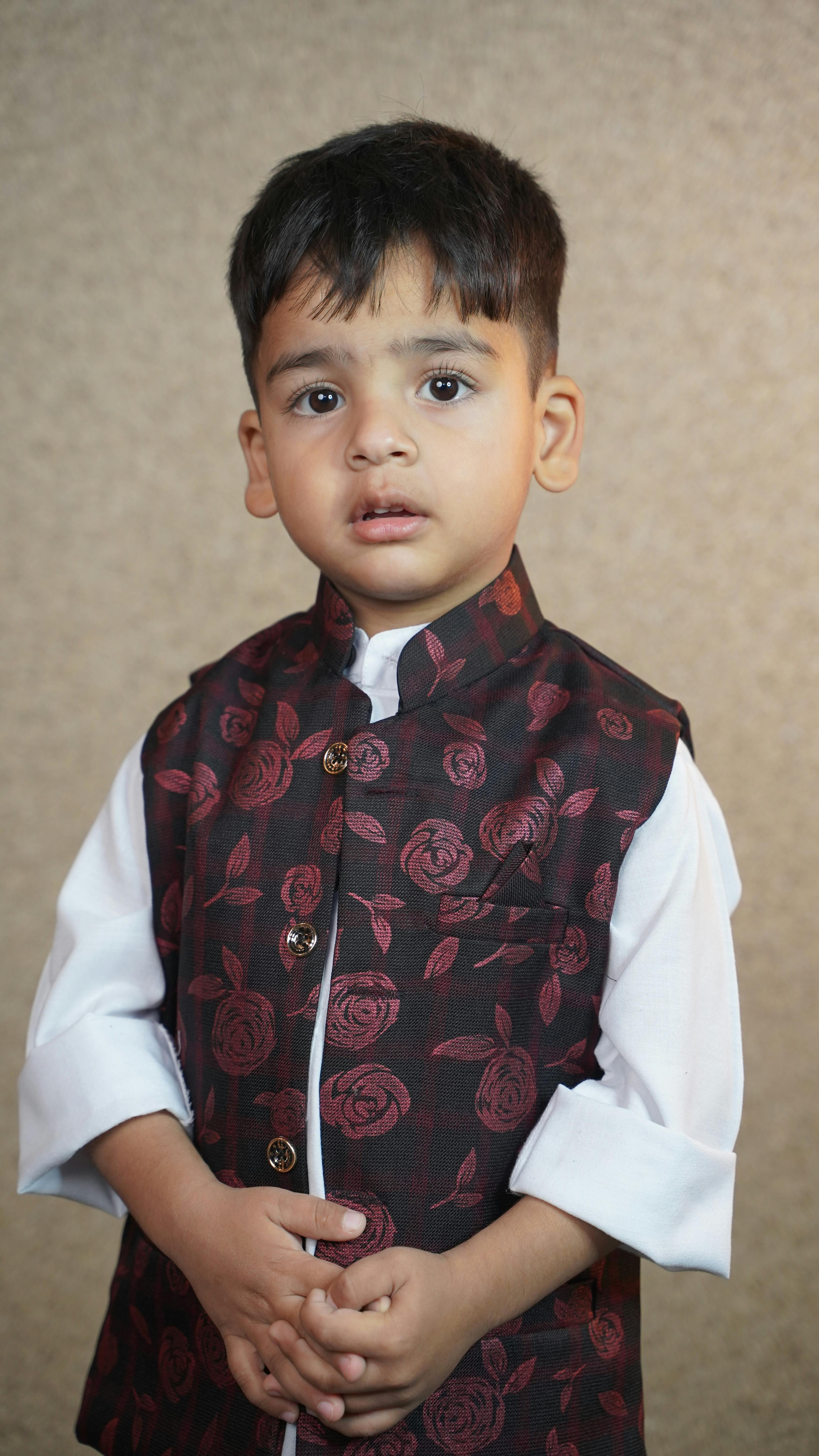 A young Kashmiri boy poses in a beautifully patterned traditional outfit, showcasing cultural heritage.