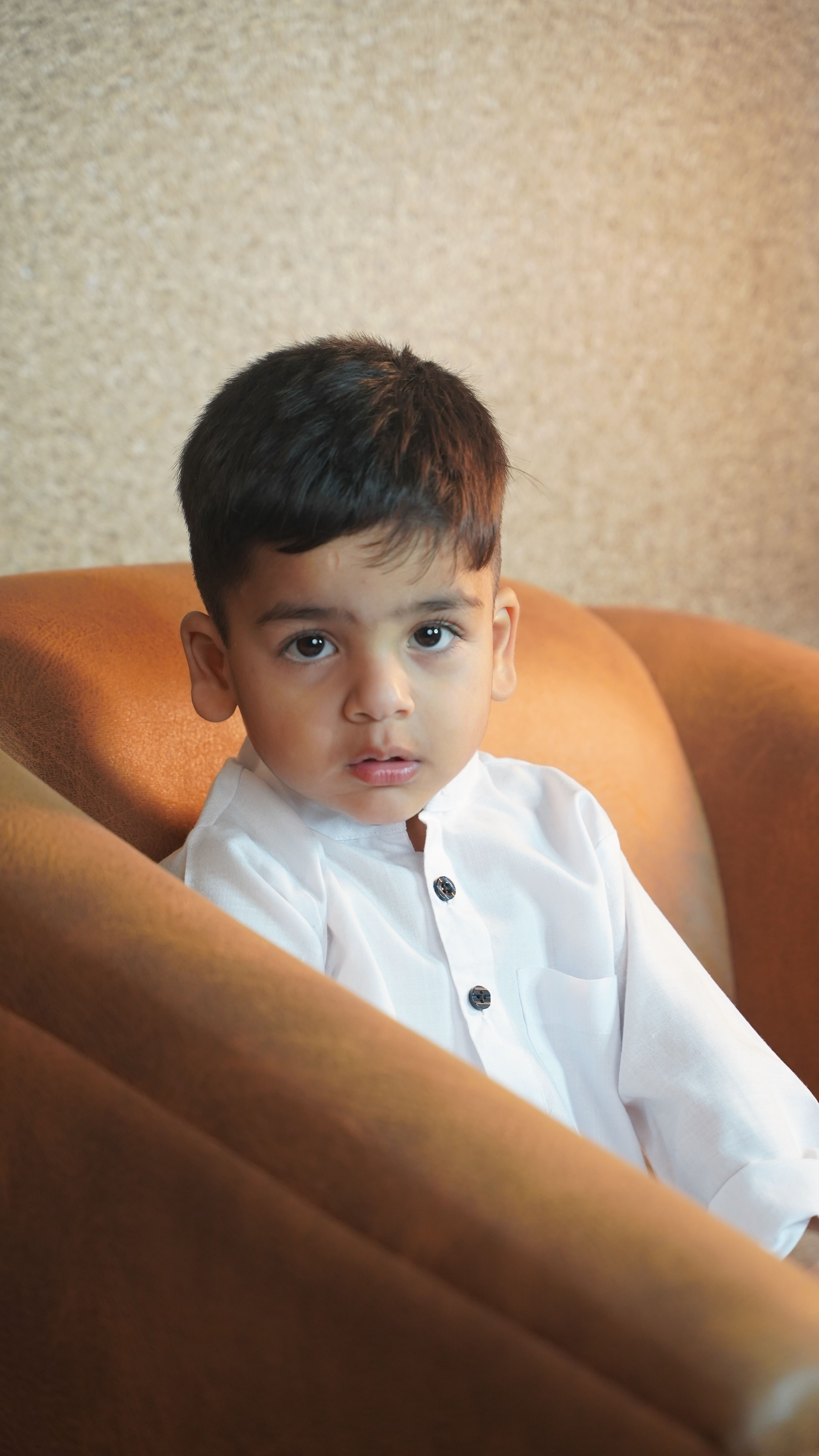 Charming portrait of a young child sitting in a cozy chair indoors.