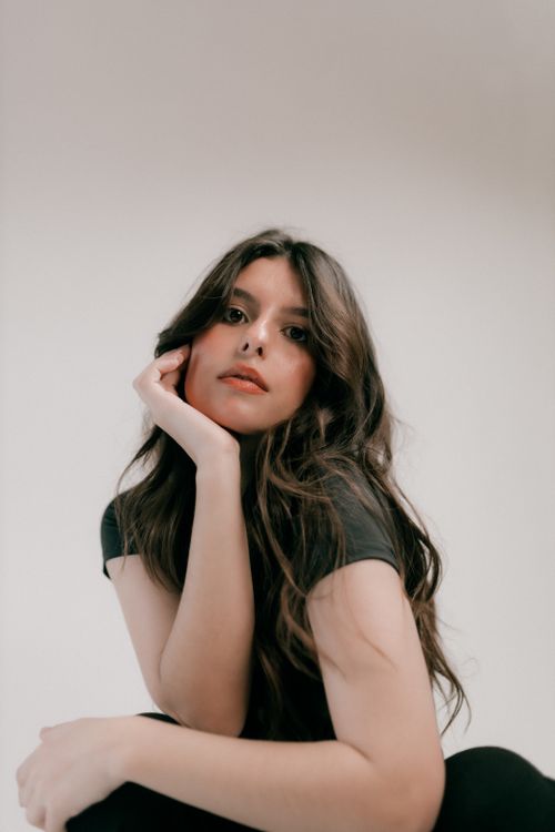 Free Portrait of a young woman with long hair posing against a neutral background. Stock Photo