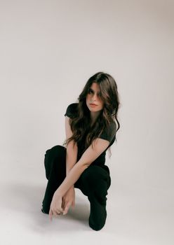 Stylish woman with long hair posing in a minimalistic studio setting.