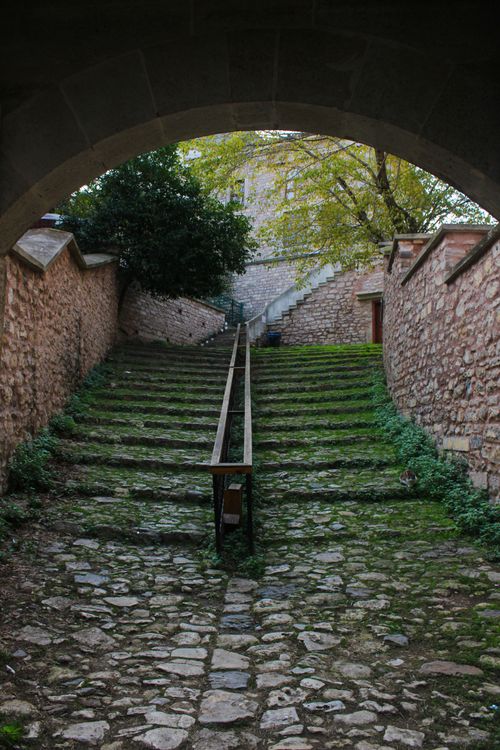 Free Historic stone staircase under archway, lush with greenery, outdoor setting. Stock Photo