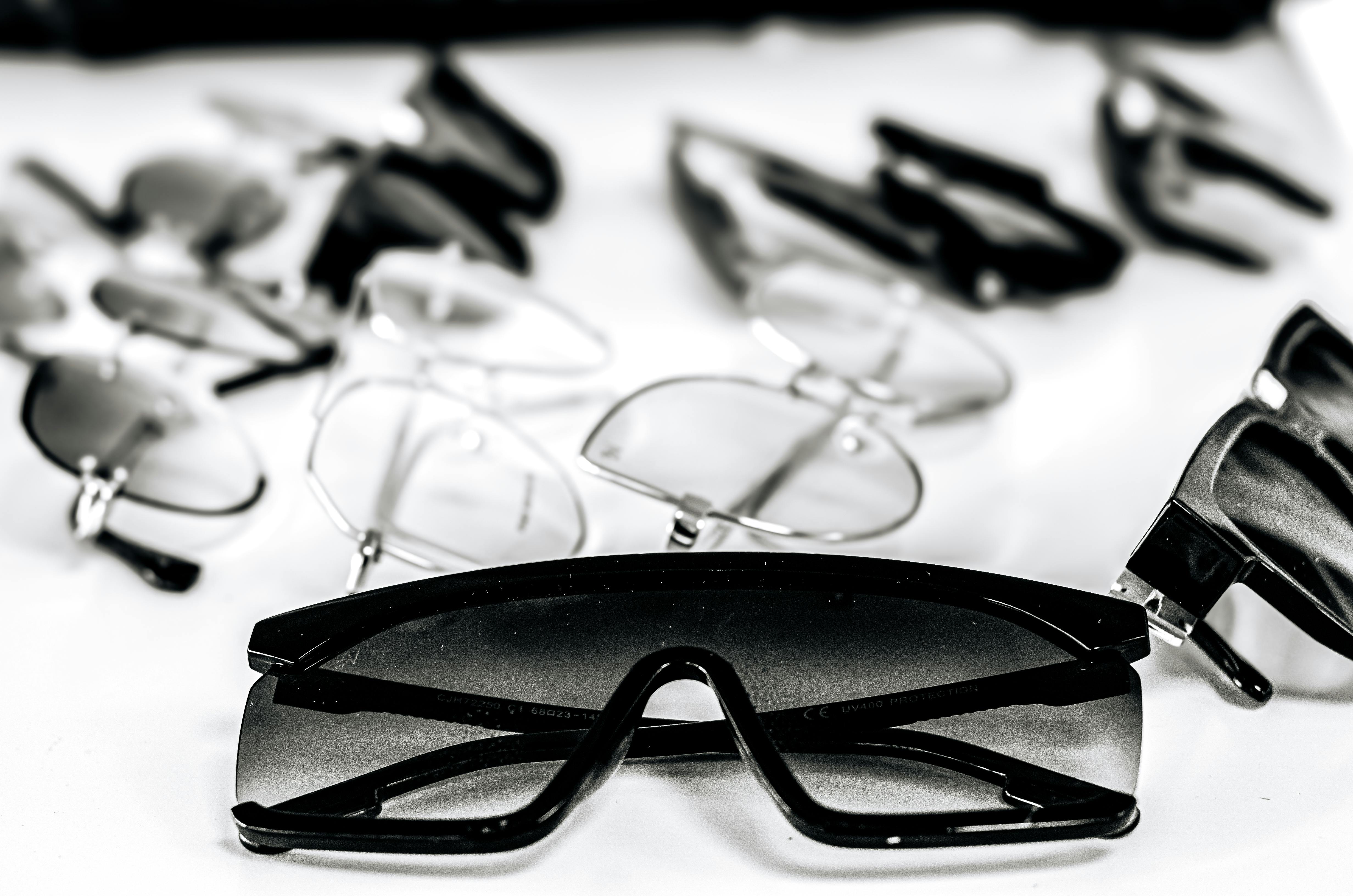 Close-up of various stylish sunglasses and eyeglasses on a white surface, showcasing modern eyewear design.
