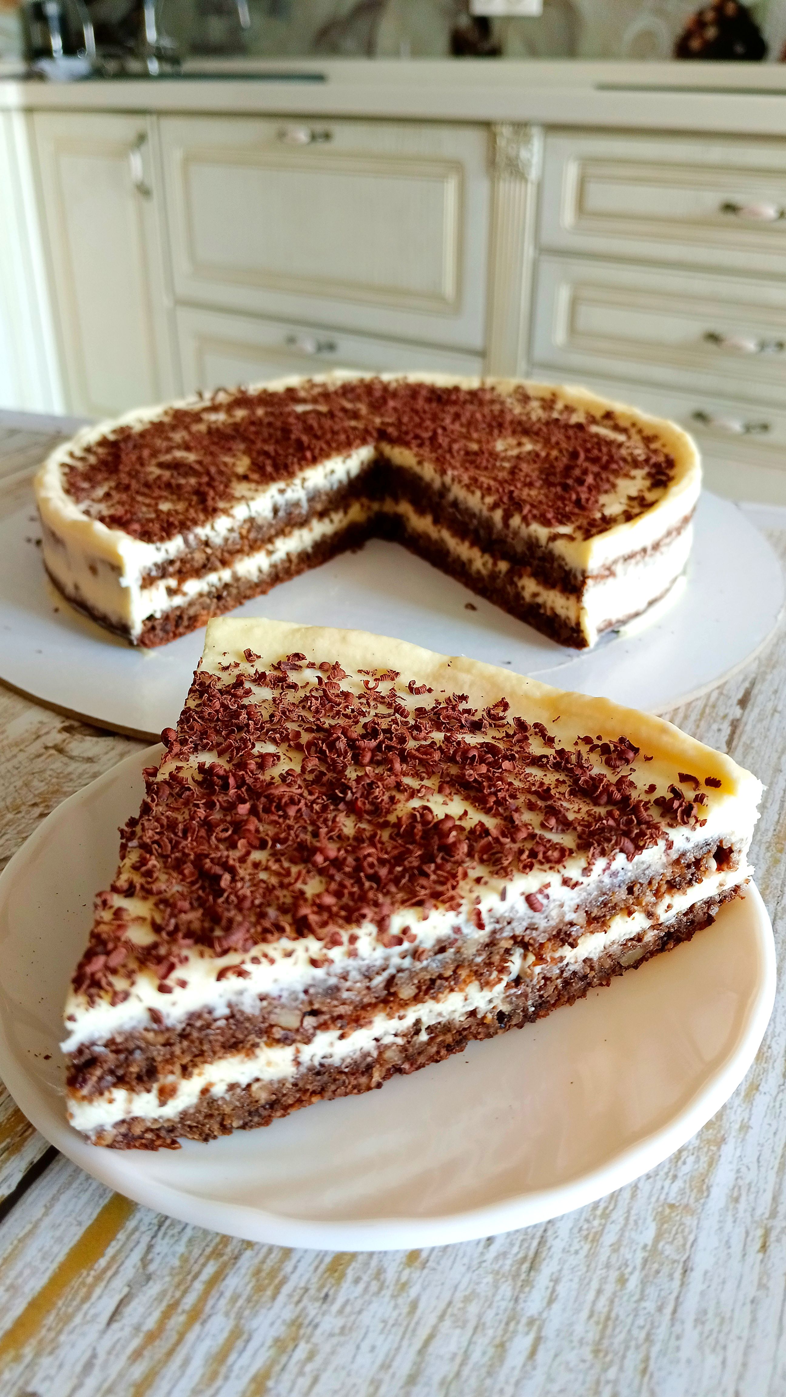 Mouth-watering chocolate layer cake with cream frosting in a cozy kitchen setting.