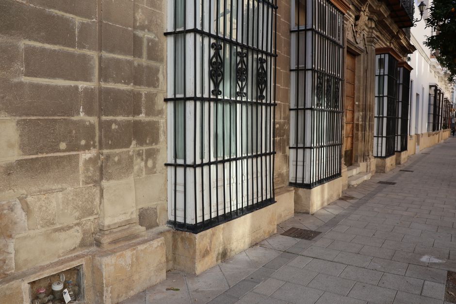 Encantadora fachada histórica de calle en El Puerto de Santa María, Andalucía, que muestra ventanas enrejadas y arquitectura clásica.