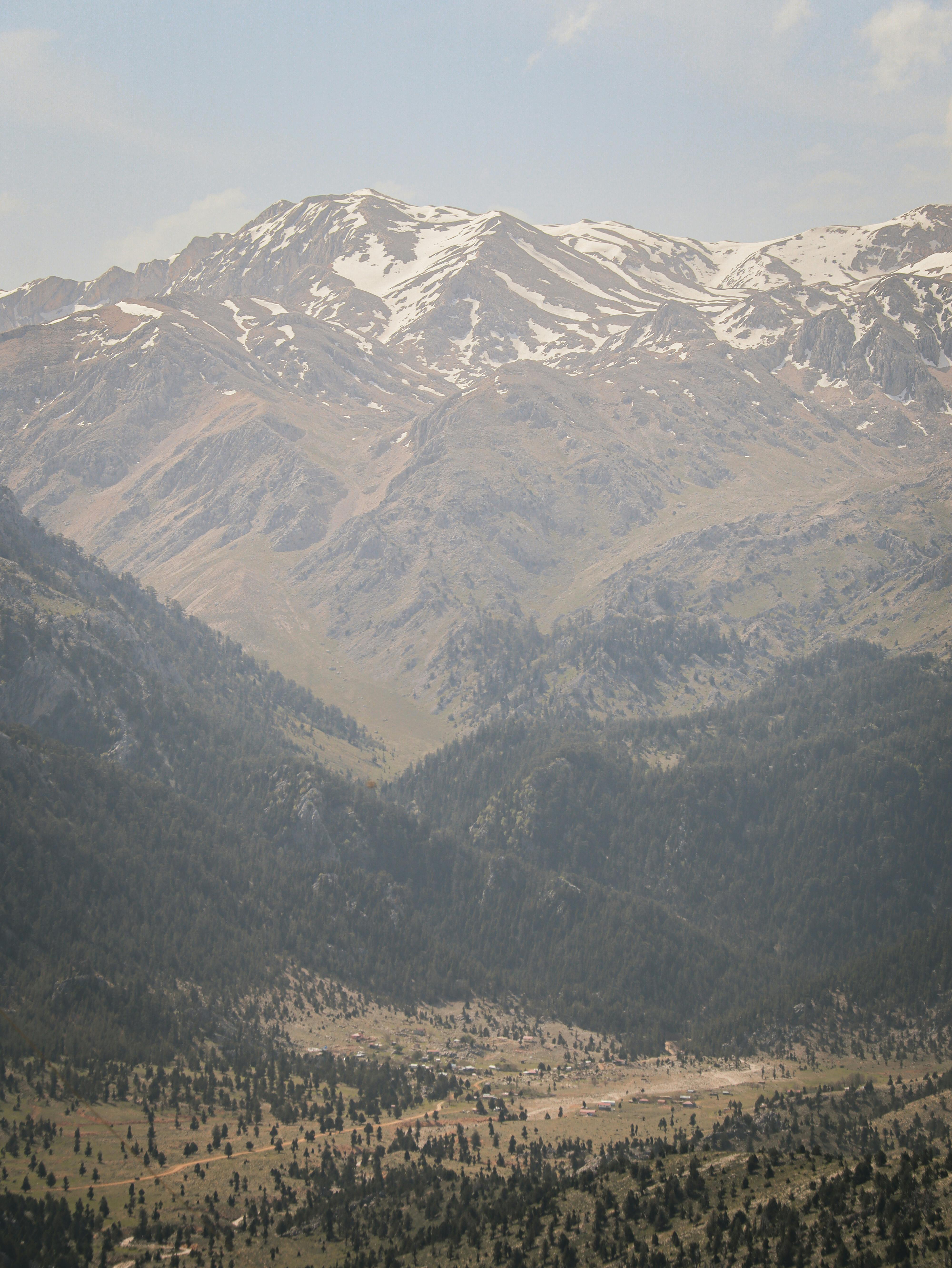 Breathtaking view of snow-capped mountains with a lush valley below, captured in beautiful natural light.