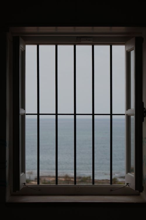 Free A serene ocean view through window bars creating a frame effect, evoking peace. Stock Photo