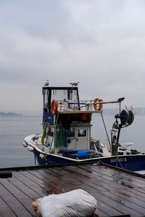 Free A fishing boat is docked on a rainy day in İstanbul, Türkiye, capturing the tranquil maritime scene. Stock Photo