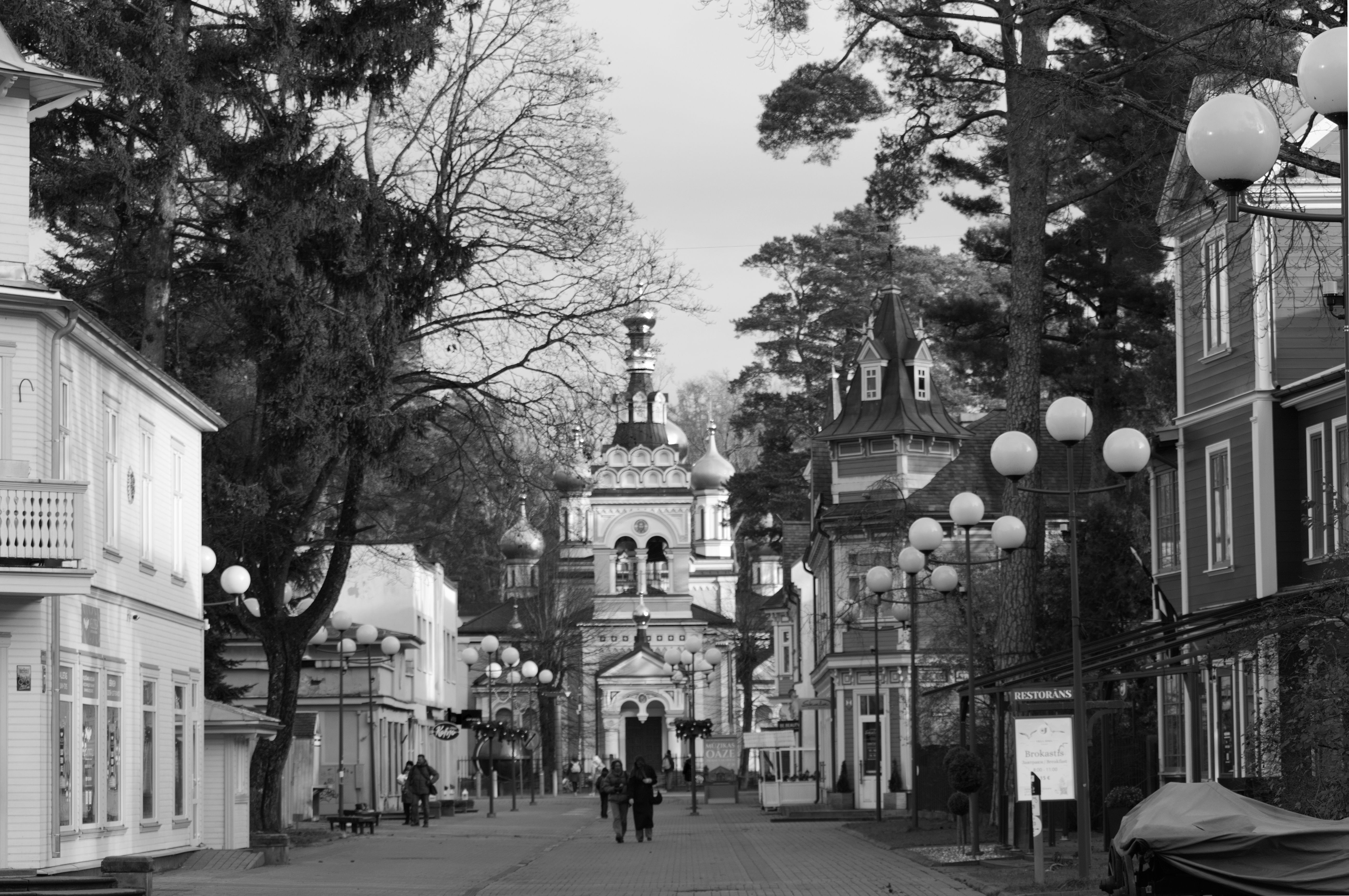 A black and white photo capturing a historic city street with church architecture and street lamps.